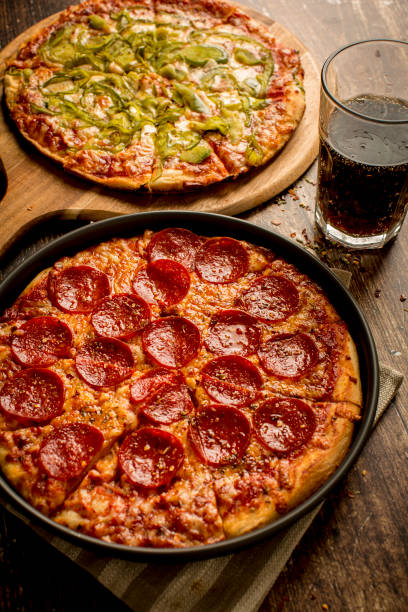 istock Green pepper pizza and Pepperoni pizza on wood table 1379284083