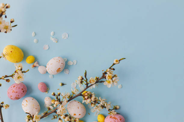 istock Colorful Easter chocolate eggs with cherry blossoms on blue background. Happy Easter! Stylish tender spring template. Easter flat lay with space for text. Greeting card or banner 1379285165