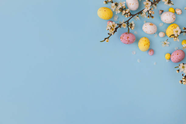 istock Easter flat lay with space for text. Colorful Easter chocolate eggs with cherry blossoms on blue background. Happy Easter! Stylish tender spring template. Greeting card or banner 1379289529