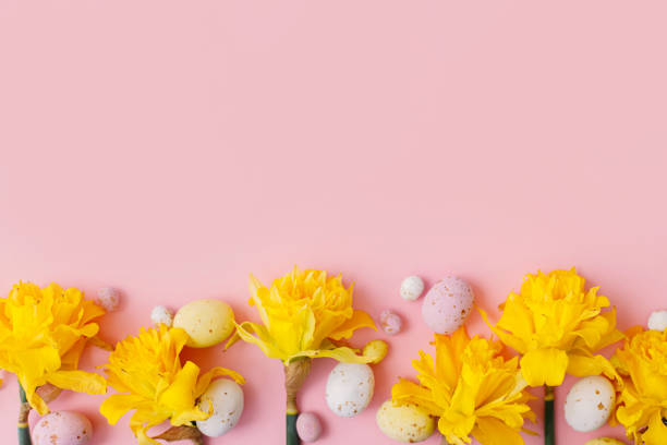 istock Colorful Easter chocolate eggs and daffodils flowers border on pink background. Happy Easter! Stylish Easter flat lay. Greeting card or banner template 1379292777