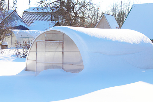 Snow-covered greenhouse in the garden. Close-up. Background.