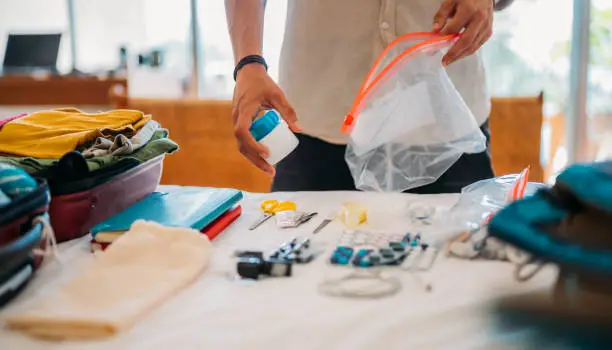 An unrecognizable man packs tablets and vitamins in transparent plastic bags with a zipper.