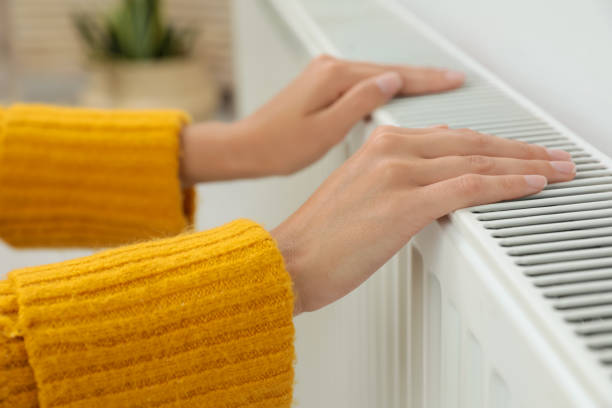 istock Woman warming hands on heating radiator indoors, closeup 1379341408