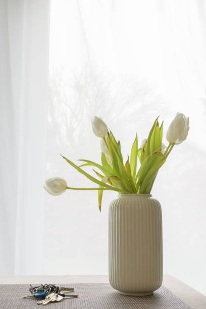 istock flowers withering  in a vase and keys left on the table. Concept vertical format 1379342000