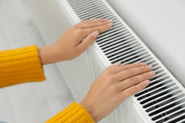 istock Woman warming hands on heating radiator indoors, closeup 1379346244