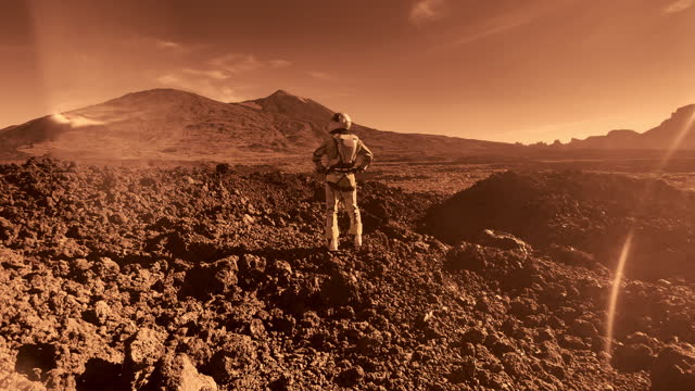 A walk on Mars. Female astronaut exploring rust mountains. Red sunlight and dust
