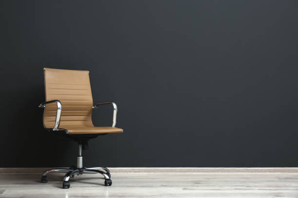 istock Comfortable office chair near black wall indoors. Space for text 1379379715