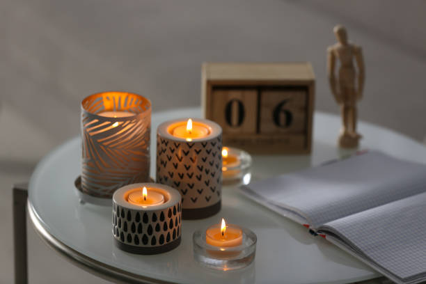 istock Burning candles in holders and notebook on white table indoors 1379380844