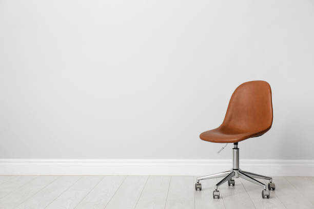 istock Comfortable office chair near light wall indoors. Space for text 1379381429