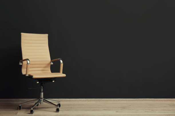 istock Comfortable office chair near black wall indoors. Space for text 1379385850