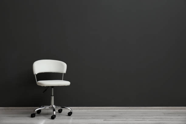 istock Comfortable office chair near black wall indoors. Space for text 1379386369