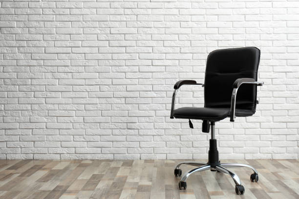 istock Comfortable office chair near white brick wall indoors. Space for text 1379386402