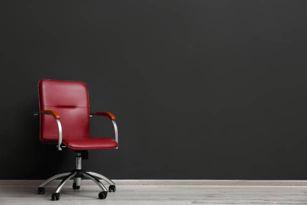 istock Comfortable office chair near black wall indoors. Space for text 1379386919