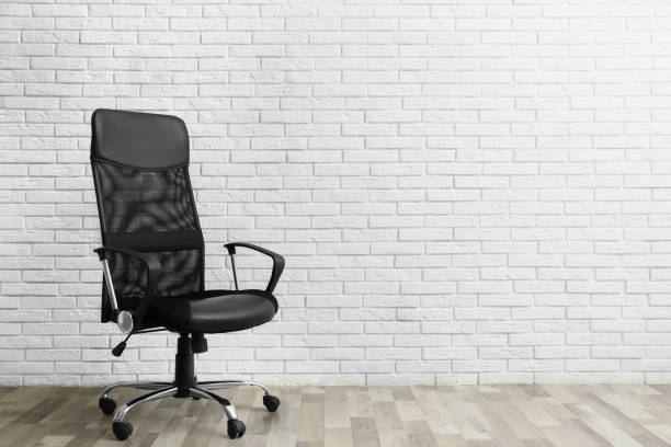istock Comfortable office chair near white brick wall indoors. Space for text 1379389123