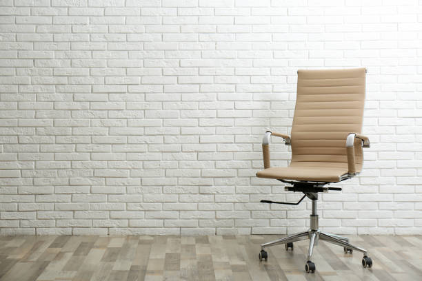 istock Comfortable office chair near white brick wall indoors. Space for text 1379389124