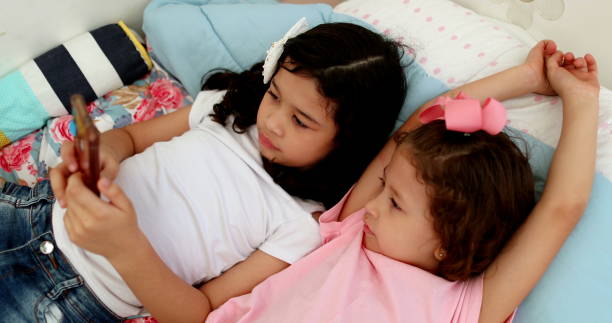 istock Two children watching video on smartphone device at home 1379390260