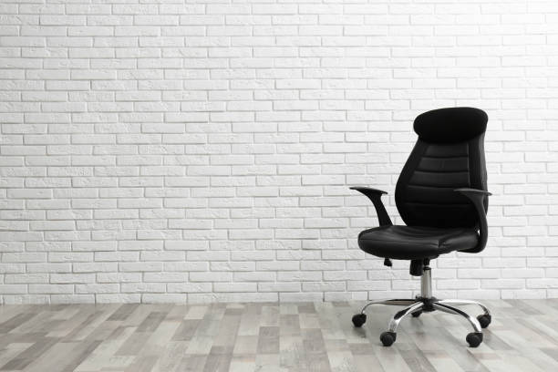 istock Comfortable office chair near white brick wall indoors. Space for text 1379390416