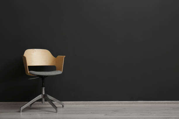 istock Comfortable office chair near black wall indoors. Space for text 1379390420