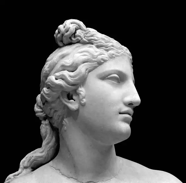 A copy of a bust of an ancient Greek goddess, Aphrodite. Aphrodite is the Greek goddess of love and beauty. Statue in Black and white isolated on a black background.