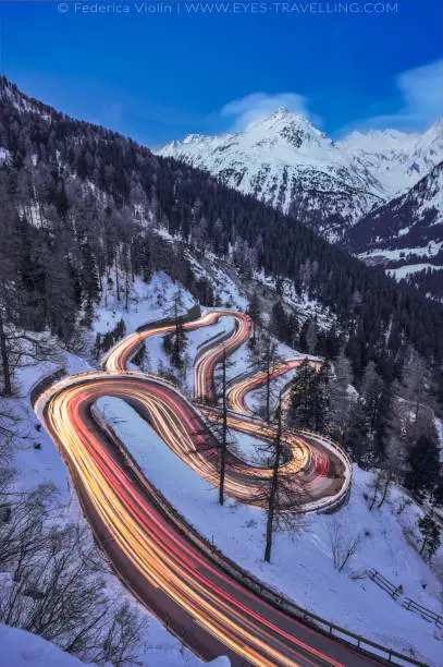 Long exposure with light trails of the Maloja Pass road in Engadin during blue hour in winter, Switzerland