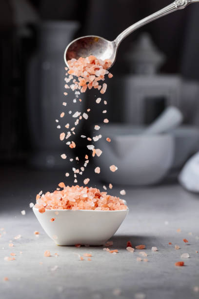 istock Pink salt in crystals is poured into a small white bowl. 1379412543