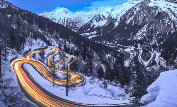 Long exposure with light trails of the Maloja Pass road in Engadin during blue hour in winter, Switzerland Long exposure with light trails of the Maloja Pass road in Engadin during blue hour in winter, Switzerland maloja region stock pictures, royalty-free photos & images