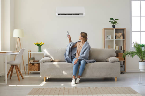 woman enjoying cool fresh air in her living room with air conditioner on the wall - home accessories imagens e fotografias de stock