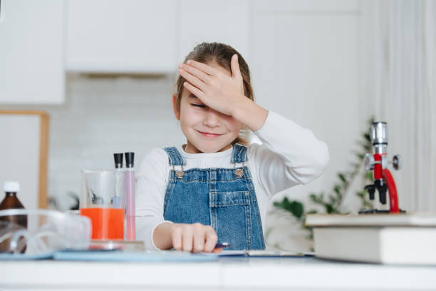 istock Funny little girl doing home science project, making facepalm 1379416542