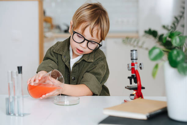 istock Cute little boy doing science project, filling glass chemical dish from a beaker 1379417424