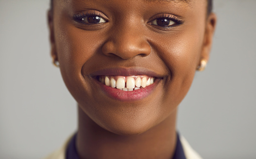 Close up portrait of a happy young black woman with a charming white toothy smile
