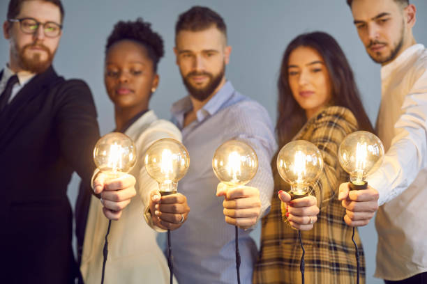 istock Team of people looking at glowing light bulbs, determined to implement new business ideas 1379421794