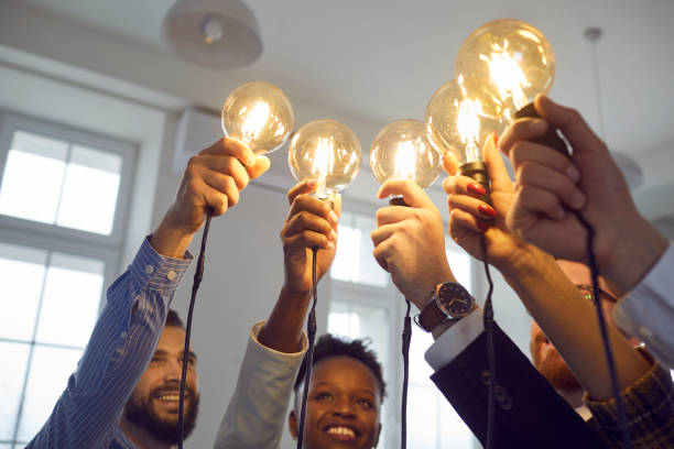 istock Interracial group of people standing together with raised lightbulb office shot 1379421804