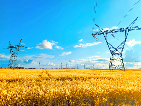 Electricity background banner panorama - Voltage power lines / high voltage electric transmission tower with blue sky and shining sun