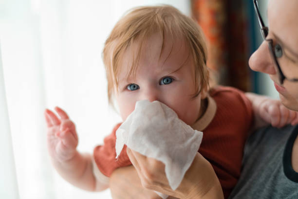 Mother cleaning nose of her baby girl stock photo