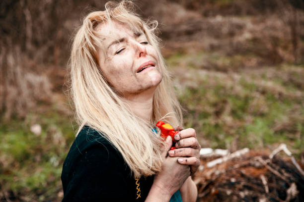 Crying sad hopeless Woman holding toy car in emotional pain. Female with with burnt face at distroyed home after Natural disaster, Earthquake, stormy weather, Bombing or War.  Selective focus