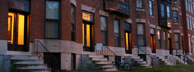 Warm light emanates from a row of doorways at dusk.  Charles Village, Baltimore, MD.