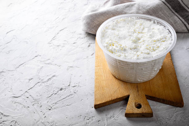 queso ricotta y tabla de cortar de madera sobre fondo de yeso blanco. espacio para texto. - cheese softness freshness food fotografías e imágenes de stock