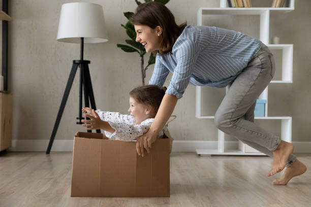 istock Happy mom laughing, dragging box with screaming little daughter 1379515096