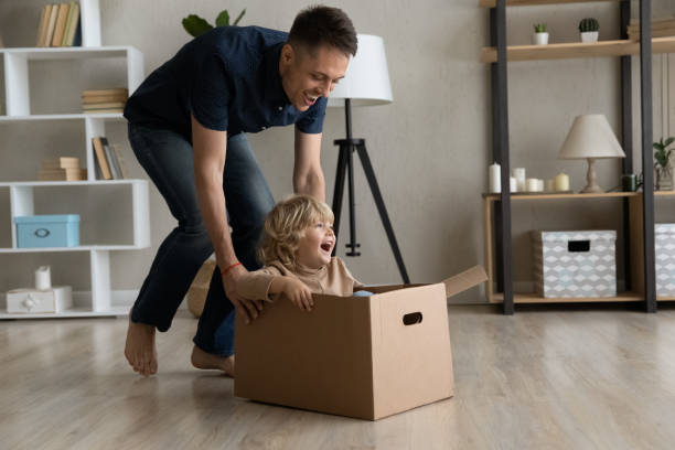 istock Cheerful dad shifting cardboard box with happy little son inside 1379515099