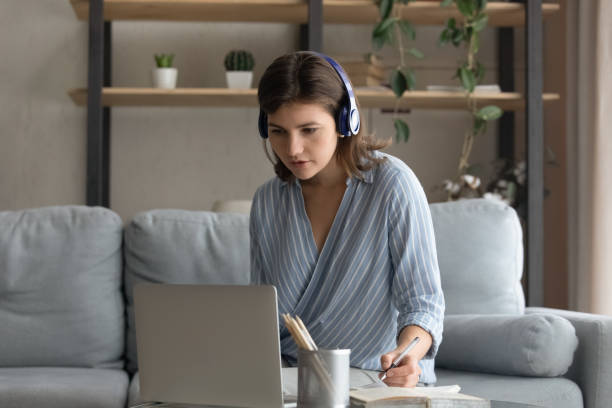 istock Focused millennial student woman in wireless headphones writing notes 1379518843
