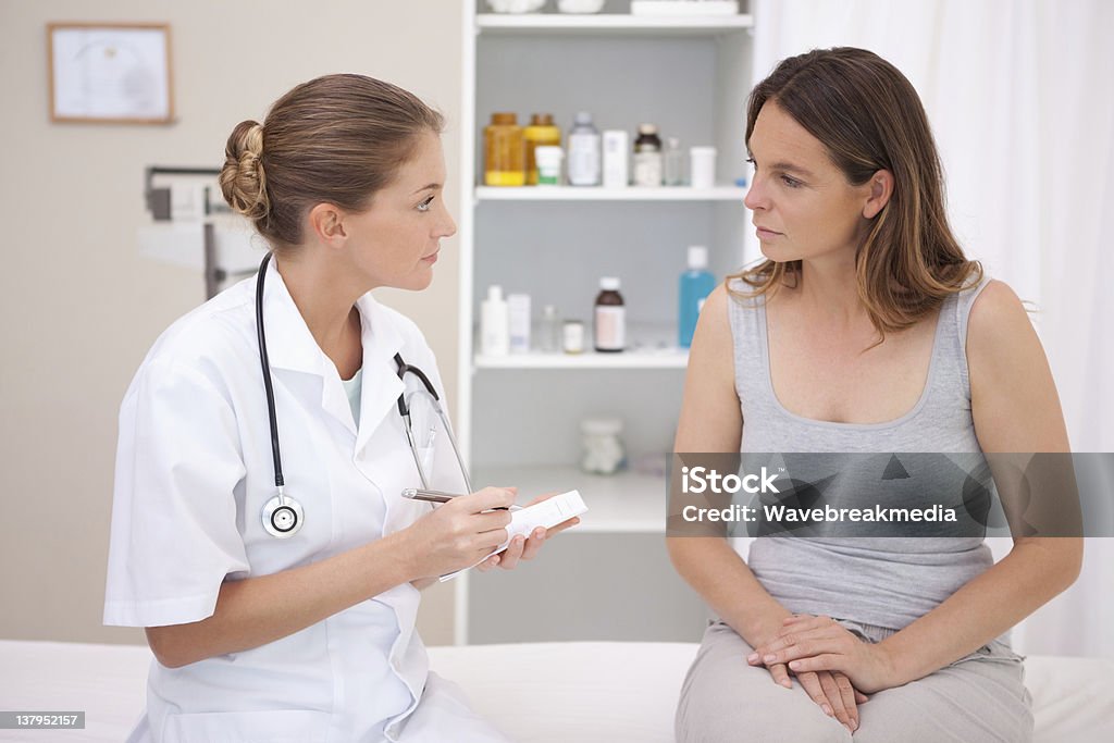 Doctor taking notes Doctor taking notes while patient is talking Discussion Stock Photo