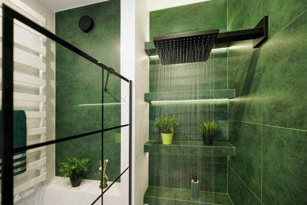 Water running from a black rain shower head in a green luxury bathroom stock photo