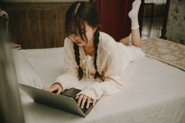 istock A beautiful asian girl who works on a computer in bed 1379547811