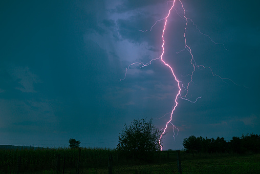 Powerful pink lightning bolt hits the ground in the countryside of Transylvania, Romania.