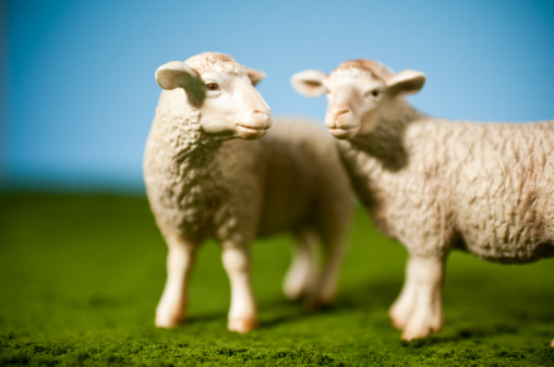 Miniature toy sheep on artificial grass.