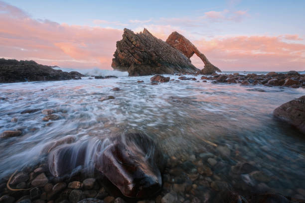 Landscape of natural sea arch and stones in the foreground covered with water stock photo