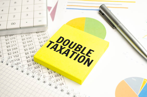 open notebook in a closed notebook. near the calculator.text on white paper. DOUBLE TAXATION
