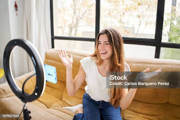 Modern Influencer Female Vlogger Making Social Media Video While Sitting Indoors Sofa Home Shooting With Mobile Smart Phone Camera Stock Photo - Download Image Now