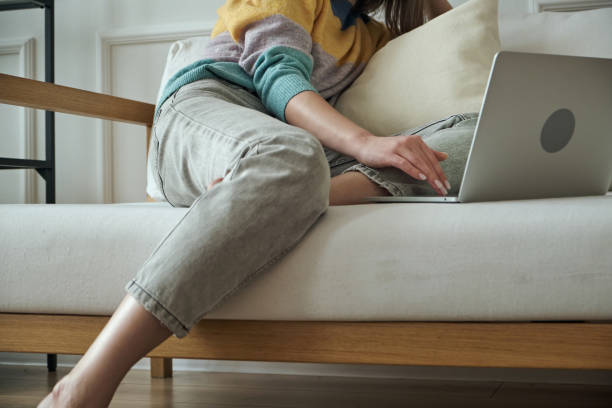istock Young woman using laptop, typing, using touchpad, sitting at home on sofa, remote work, work at home 1379588226