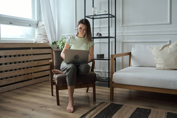 istock Young woman using laptop, typing, sitting in a chair, remote work, work at home 1379589819